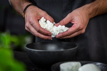 Feta wird in eine schwarze Schüssel gegeben.
