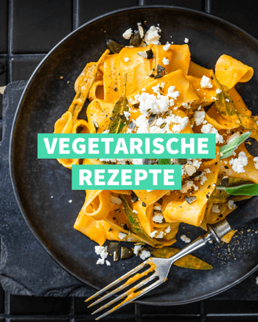 Ein Teller Pasta mit Kürbissauce auf dunklem Untergrund