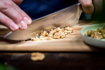 Walnüsse werden auf einem Holzbrett mit einem großen Messer gehackt