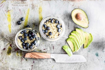 Heidelbeeren liegen in den Gläsern, daneben geschnittene Avocado-Stücke