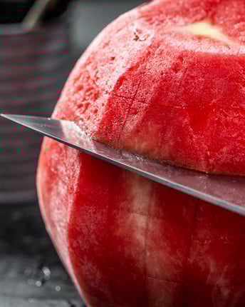 Eine geschälte Wassermelone, die kreuzförmig eingeschnitten wird