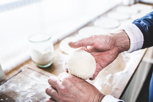 Pizzateig wird in Händen zu einer Kugel geformt
