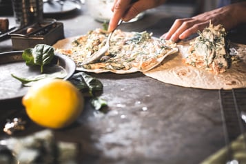 Tortillafladen werden mit einem Löffel mit einer stückigen Masse bestrichen