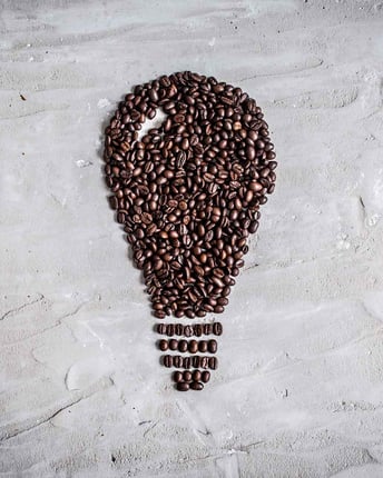 Eine Glühbirne von oben, die aus einzelnen Kaffeebohnen zusammengelegt wurde