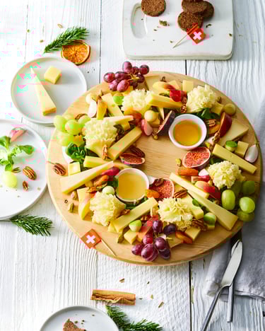 Ein Adventskranz, der aus Käse besteht auf einem Holzbrett angerichtet.