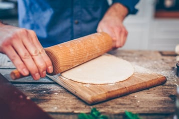 Der Teig wird mithilfe eines Nudelholzes ausgerollt und in Form gebracht.
