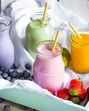 4 Smoothies mit Strohhalmen in verschiedenen Farben auf einem Tablett