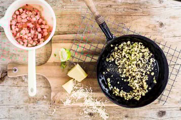 Auf einem Holzuntergrund stehen eine Pfanne, und eine Schüssel mit Rhabarber-Salsa