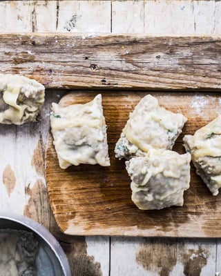 Selbstgemachte Maultaschen mit Hackfleisch und Ei auf einem Schneidebrett serviert.