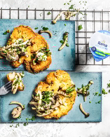 Zwei Blumenkohl-Schnitzel mit Pilzsauce auf türkisen Tellern vor weißem Hintergrund