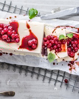 Angeschnittenes Vanilleparfait mit Johannisbeer-Senf-Sosse auf Backpapier