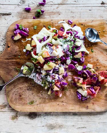 Auf einem Holzbrett ist Apfel-Rotkohl-Salat angerichtet