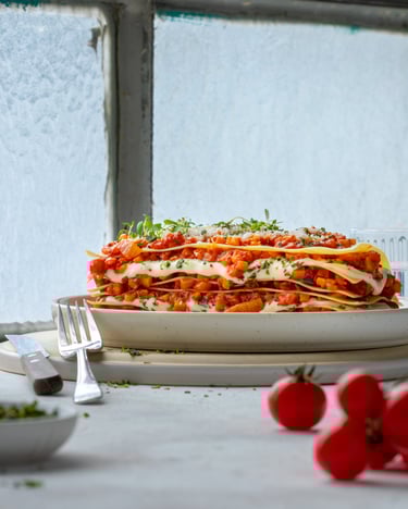Geschichtete Lasagne mit Tomaten vor hellem Fenster