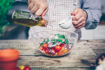 Ein Tomatensalat in einer großen Glasschüssel wird mit Öl übergossen