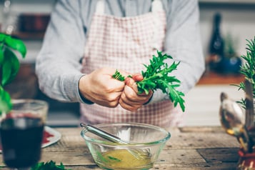 Rucola wird mit dem Dressing vermischt.