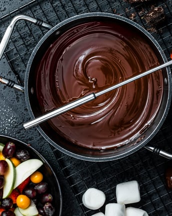 Topf mit geschmolzenem Schokoladen-Fondue und einer Schale mit Früchten