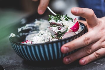 Radieschen werden unter Frischkäse-Masse gehoben