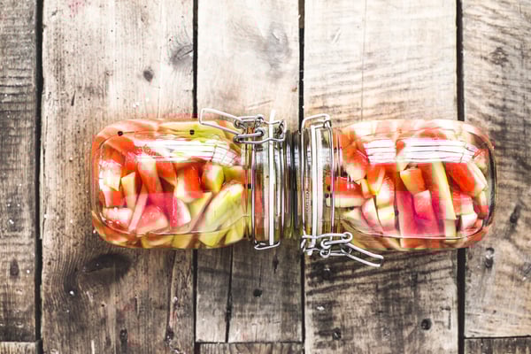 Zwei Einmachgläser mit Wassermelonenschale vor einem Holzuntergrund