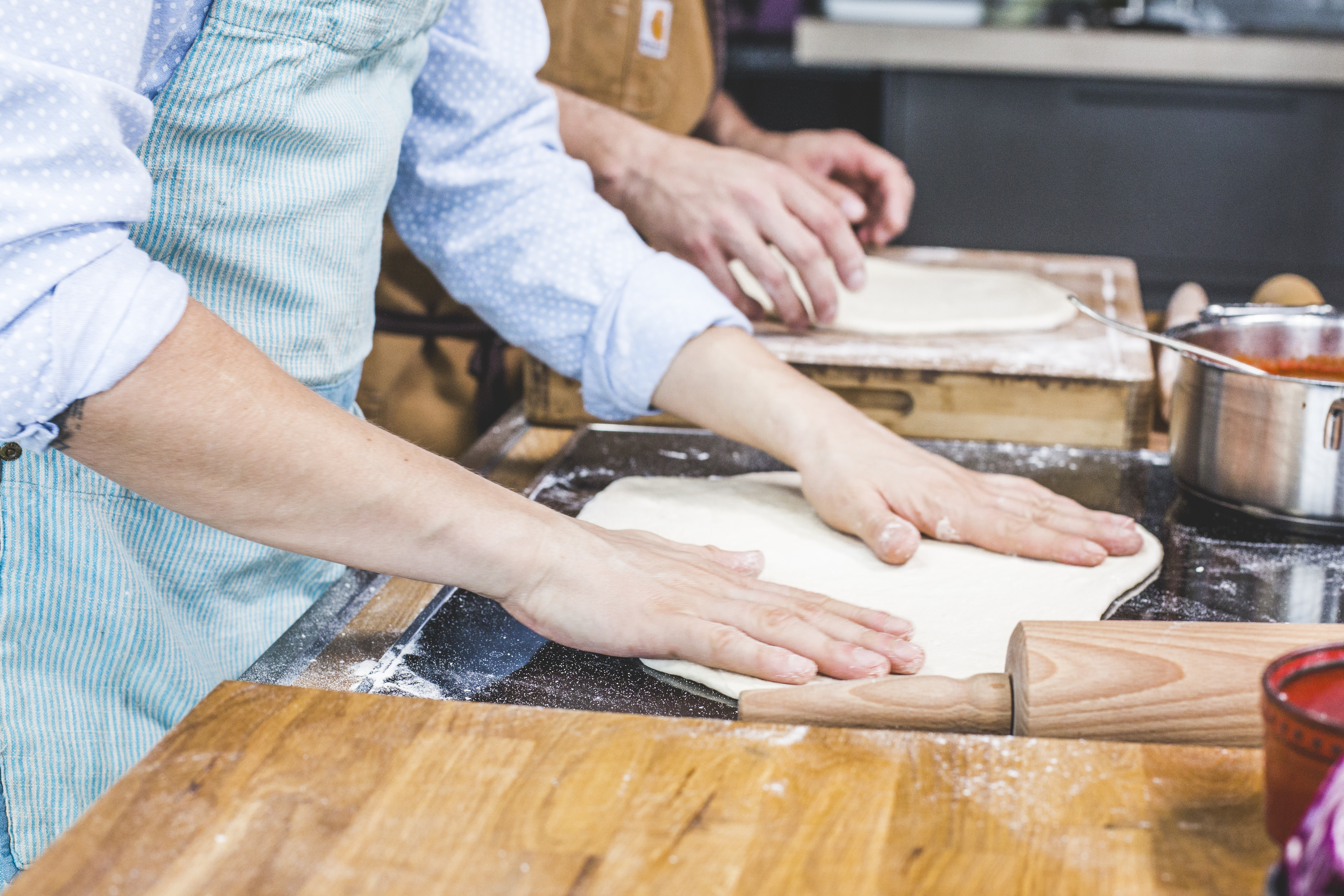 Pizzateig wird mit den Händen ausgebreitet