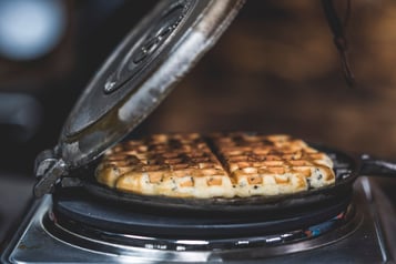 Eine Waffel mit Kräutern wird in einem Waffeleisen gebacken