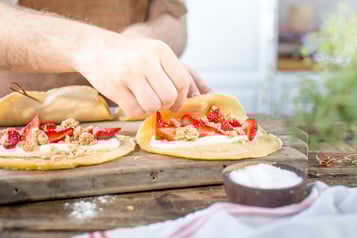 Pfannkuchen werden mit Müsli, Erdbeeren und Creme angerichtet und zusammengespießt