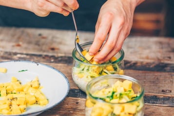 Zwei Gläser mit Porridge werden mit Mangostücken angerichtet