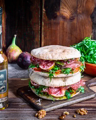 Gestapelte Focaccia mit Spianata und Rucola auf Holzbrett