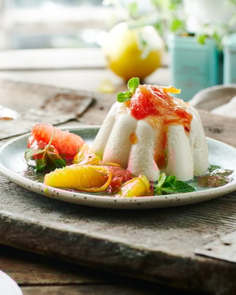 Panna Cotta und Zitruskompott auf Teller und Holz
