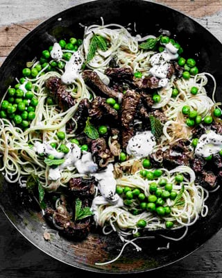 Spaghettini mit Erbsen und Rindfleisch vermengt in einer Pfanne