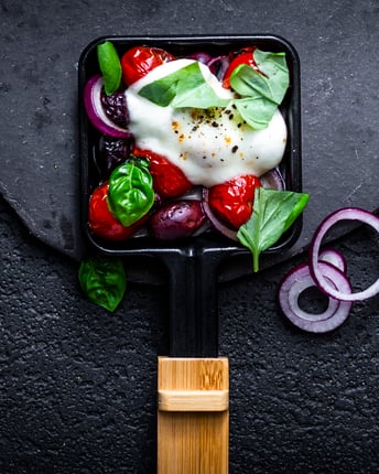 Italienisch befülltes Raclette-Pfännchen mit Tomate, Zwiebel, Mozzarella und Basilikum