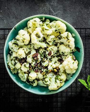 Schüssel mit Blumenkohlsalat auf dunklem Untergrund
