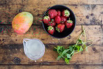 Erdbeeren in einer Schale, eine Mango, Minze und Kokos