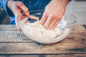 In einer Glasschüssel wird der Pizzateig geknetet.