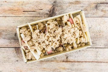 In einer Kastenform auf Holzuntergrund sind Lasagneplatten geschichtet mit Jägerschnitzel
