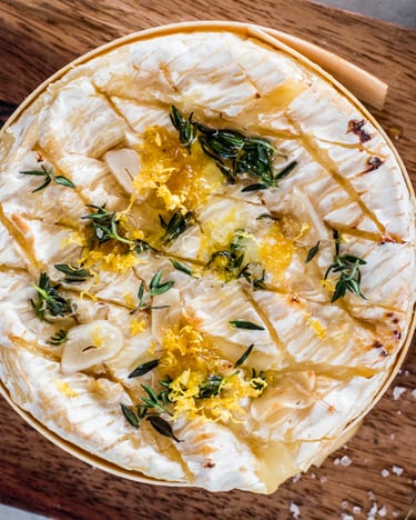 Ein Back-Camembert steht auf einem Holzbrett