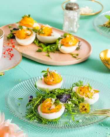 Auf einem Glasteller liegen 3 gefüllte Eier, dahinter weitere Portionen
