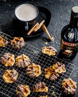 Spekulatius-Waffel-Cookies mit Baileys, fotografiert von oben, liegend auf einem Gitter, daneben Tannenzweige uind eine Flasche Baileys.