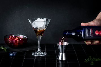 Cranberry-Nektar wird mit einem Jigger abgemessen