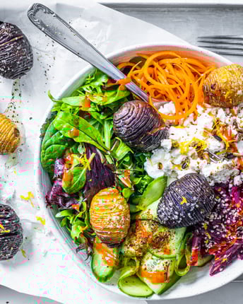 Salat-Bowl mit Möhren, Rote Bete und Hasselback-Kartoffeln auf einem Tablett