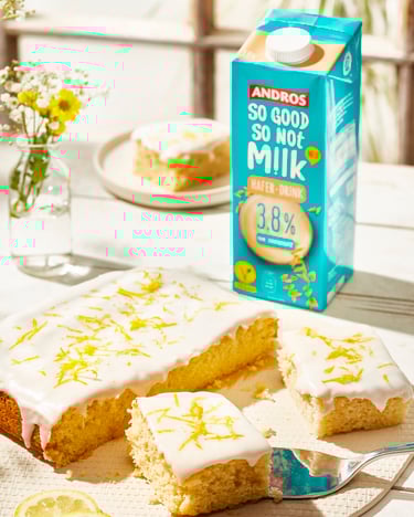 Zitronenkuchen auf einer hellen Platte. Mehrere Stücke sind geschnitten und eins liegt auf einem Tortenheber.