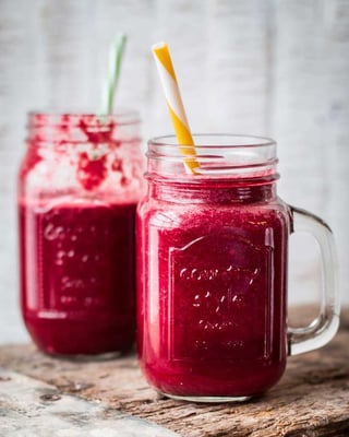 In zwei Gläsern mit Henkel ein roter Smoothie. In beiden Gläsern steckt ein Strohhalm