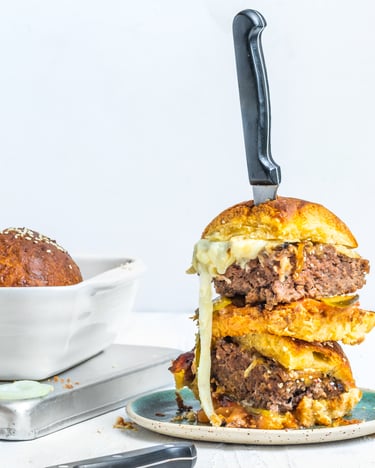 Cheeseburger-Auflauf in weißer Auflaufform und aufgetürmte Burger auf einem Teller