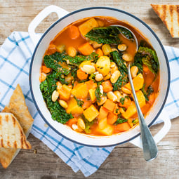 Ribollita – toskanische Bauernsuppe mit Gemüse in Topf auf Holzuntergrund