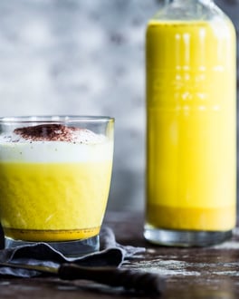 Goldene Milch in Glas und Karaffe gefüllt von der Seite