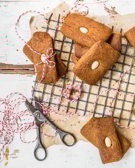 Eckige Lebkuchen mit Mandeln auf Backpapier und einem Gitter.