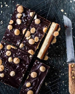 Zerschnittenes Shortbread mit Macadamianüssen, Schokolade und Karamell in einer Schale neben einem Messer