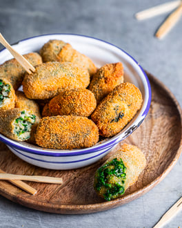 Gemüsekroketten mit Mangold in einer Schale mit Zahnstochern auf einem Holztablett