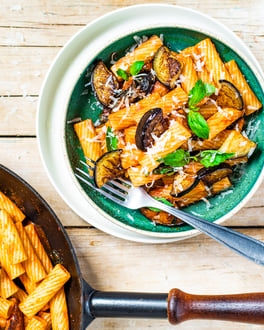 Pasta alla Norma mit Aubergine, Tomatensauce und Pecorino auf Holzuntergrund
