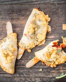 Mini-Calzone am Spieß mit Salami-Schinken-Füllung und Tomatensauce auf Holzuntergrund.