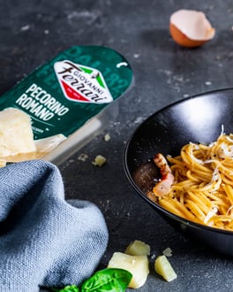Spaghetti Carbonara in Pfanne mit Käseverpackung Giovanni Ferrari im Hintergrund